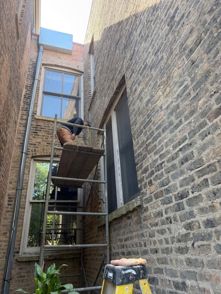 Mason on a ladder assessing the historic brick facade
